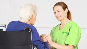 Alte Frau im Rollstuhl als Patientin mit Pflegekraft.